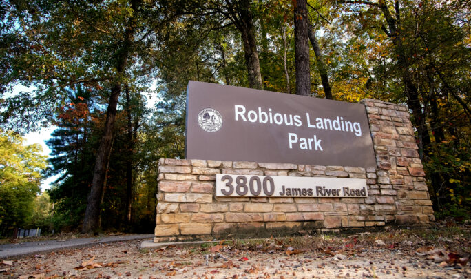 Robious Landing Park sign nestled among trees and fallen leaves.